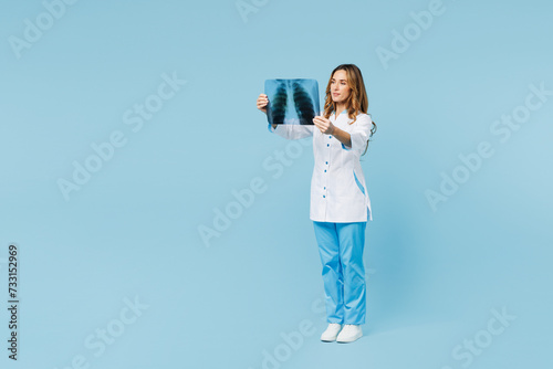 Full body female doctor woman wear white medical gown suit work in hospital clinic hold roentgen X-ray of lungs with pneumonia isolated on plain blue background studio. Health care medicine concept.