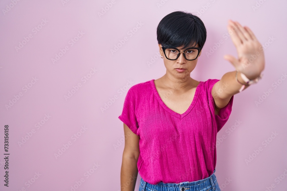 Young asian woman with short hair standing over pink background doing stop sing with palm of the hand. warning expression with negative and serious gesture on the face. Young asian woman with short hair standing over pink background doing stop sing with palm of the hand. warning expression with negative and serious gesture on the face.