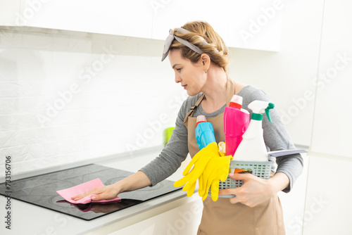 Attractive woman cleaning furniture in kitchen with a rag