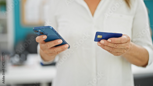 Middle age hispanic woman business worker shopping with smartphone and credit card at the office