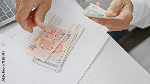Photography A man counts singaporean dollars in an office, suggesting business, finance, and economy themes