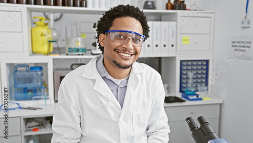 Smiling man wearing lab coat and safety goggles in scientific laboratory setting photo