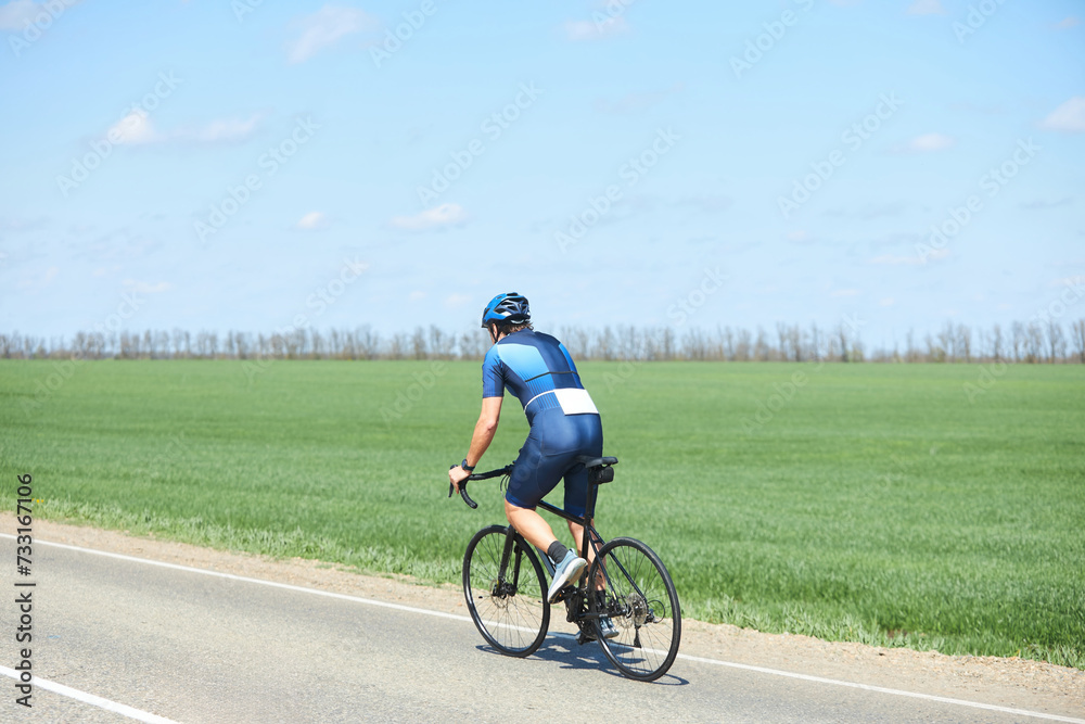 An athlete in cycling or triathlon competitions. A man in a bicycle uniform and helmet. Check-in on the highway