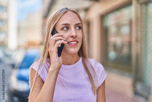 Young blonde woman smiling confident talking on the smartphone at street