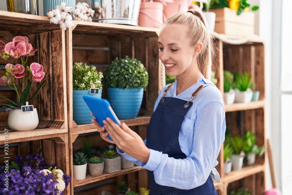 Young blonde woman florist smiling confident using touchpad at florist