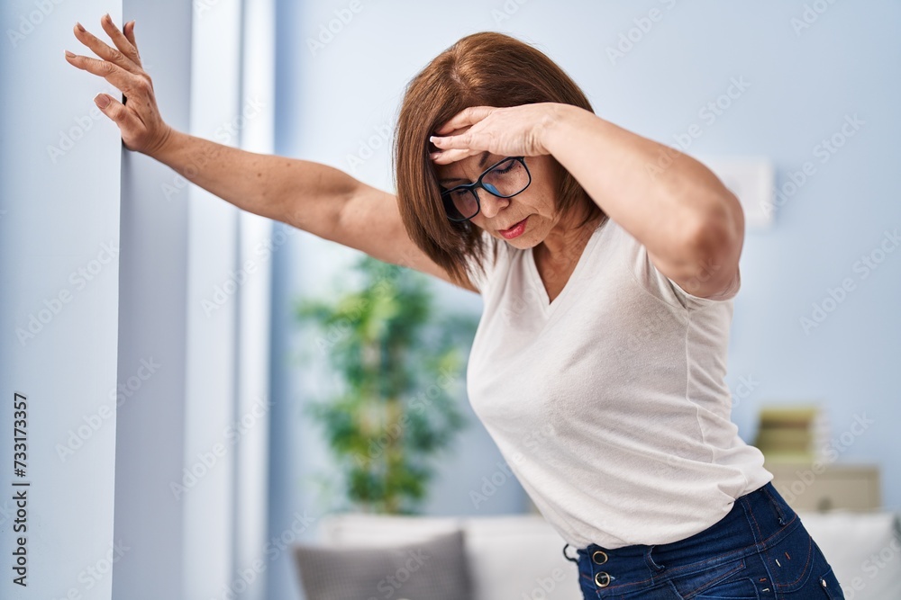 Middle age woman suffering dizzy standing at home - obrazy, fototapety, plakaty 