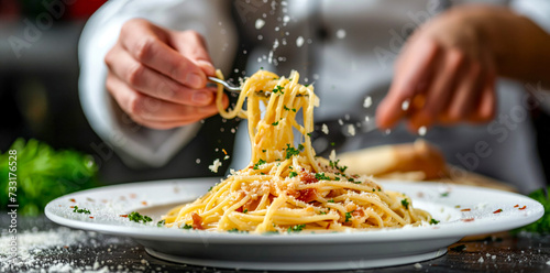 Chef Sprinkling Parmesan on Spaghetti Carbonara at Gourmet Restaurant 