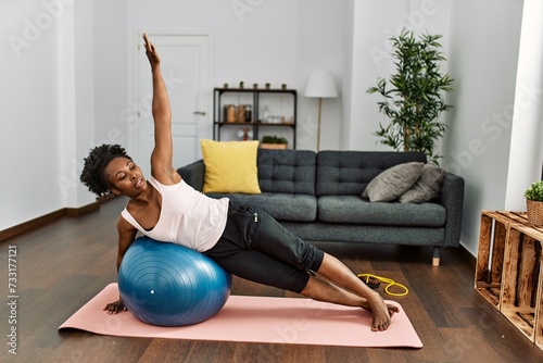 African american woman training abs exercise using fit ball at home
