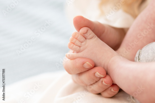 the parent's hand holds the baby's small leg, light close-up photo. family concept. background with place for text