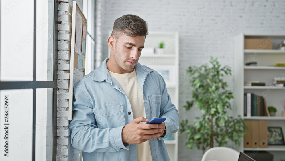 Young hispanic man business worker using smartphone at the office
