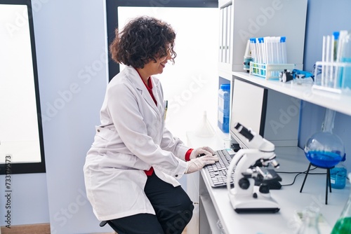 Young beautiful hispanic woman scientist smiling confident using computer at laboratory