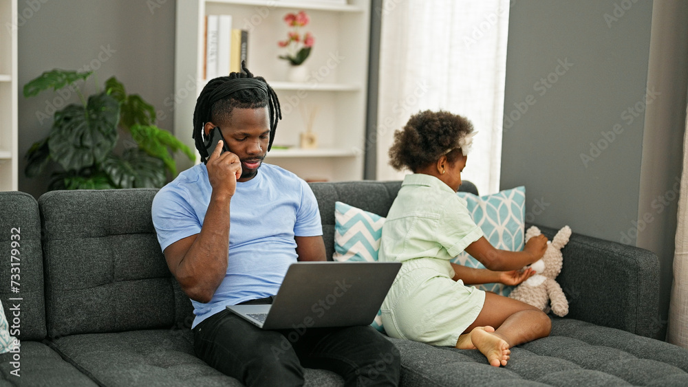 African american father and daughter sitting on sofa working and playing at home African american father and daughter sitting on sofa working and playing at home