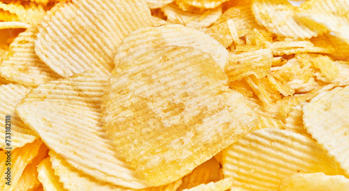 Close-up of crisp, textured potato chips piled together, emphasizing the concept of snacking and indulgence.