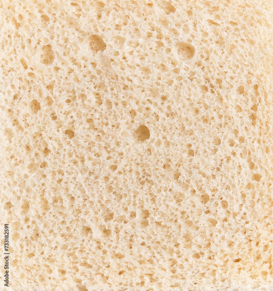 Close-up texture of a slice of white bread showcasing its porous structure and fine details.