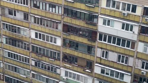 Panoramic view of a residential multi-storey building from the times of the USSR. Old and gloomy panel apartment with balconies. Soviet city residential buildings on a cloudy winter day.