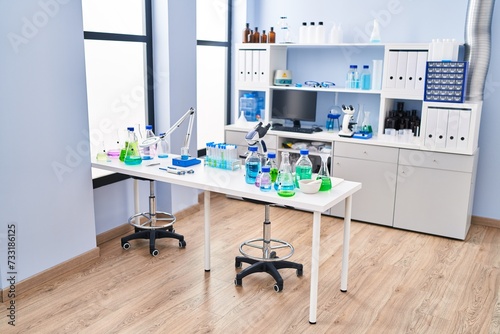 Modern laboratory interior with scientific research equipment on the desk and shelves filled with files and bottles.
