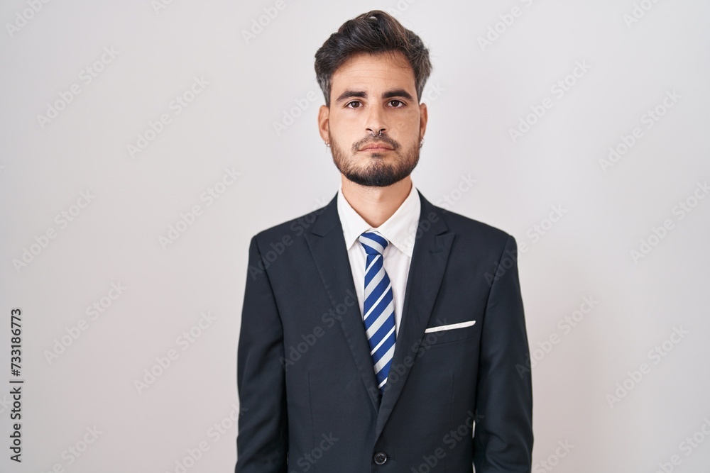 Young hispanic man with tattoos wearing business suit and tie relaxed with serious expression on face. simple and natural looking at the camera. Young hispanic man with tattoos wearing business suit and tie relaxed with serious expression on face. simple and natural looking at the camera.