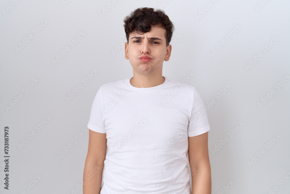 Fototapeta premium Young non binary man wearing casual white t shirt puffing cheeks with funny face. mouth inflated with air, crazy expression.