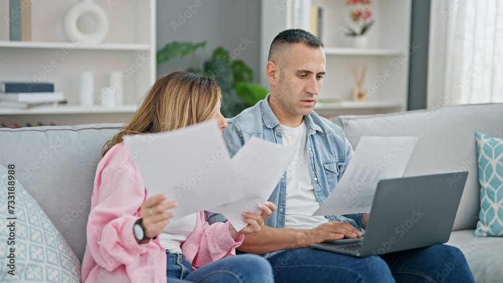 Man and woman couple using laptop reading document at home
