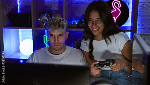 A man and woman enjoy gaming together in a cozy, neon-lit room at night, reflecting a modern couple's indoor leisure time.