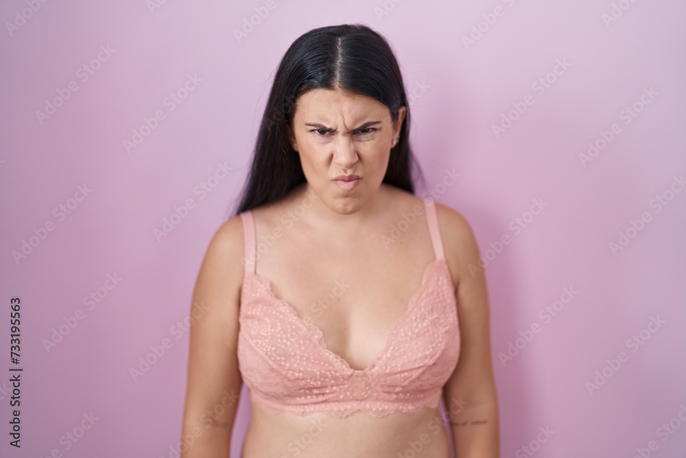 Young hispanic woman wearing pink bra skeptic and nervous, frowning upset because of problem. negative person. Young hispanic woman wearing pink bra skeptic and nervous, frowning upset because of problem. negative person.