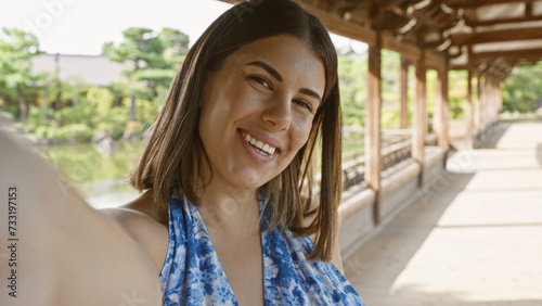 Confident hispanic woman, an all-smile beautiful brunette, enjoys taking a fun selfie at traditional japanese heian jingu shrine, kyoto. photo