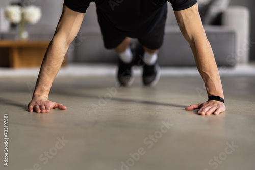 Young man looking at smartphone and doing plank exercise at home