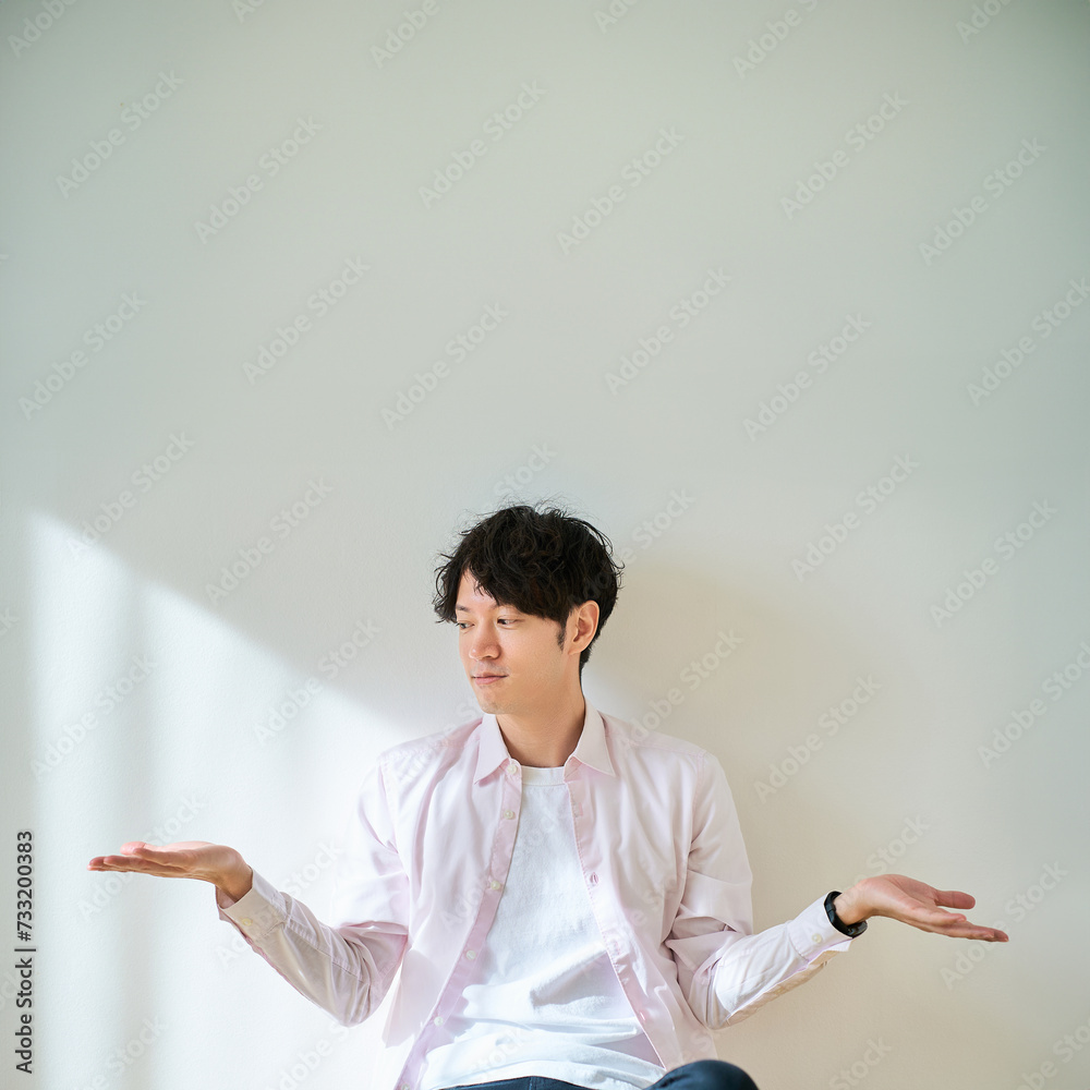 2つの選択肢を比較するようなポーズをする若い男性