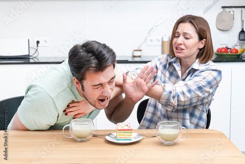 A young couple is sitting in the kitchen and ready to eat a delicious cake. Husband and wife fight over the most delicious cake