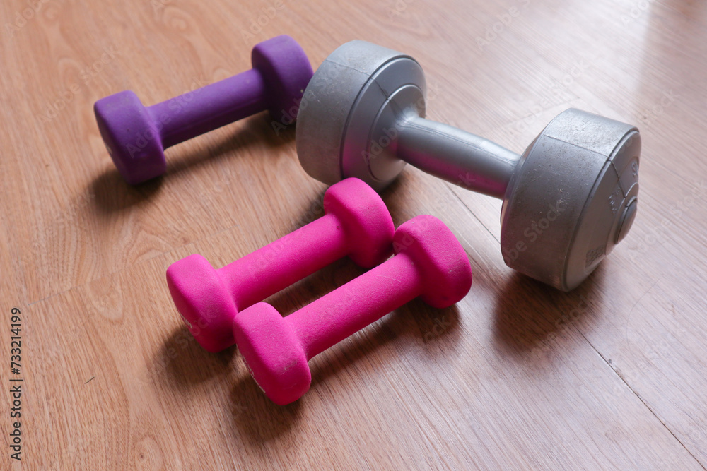 dumbbells with plastic coating on a wooden background dumbbells with plastic coating on a wooden background