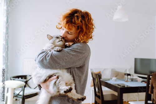 Portrait red-haired curly young woman with beloved fluffy domestic cat