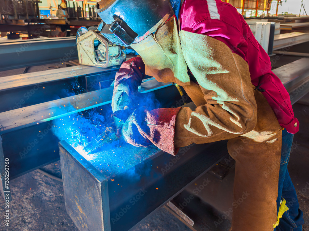 Φωτογραφία Welder Welding Steel Plate for Steel Structure Work with Process Flux Cored Arc Welding (FCAW) and Appropriately Dressed with Personal Protective Equipment (PPE) for Safety, at an Industrial Factory