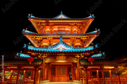 Chinese temple with roof at night with a lady in sight