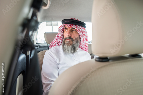 Arab senior businessman wearing traditional emirati kandora strolling in the city - Middle-eastern senior adult with dishdasha clothing portarit photo