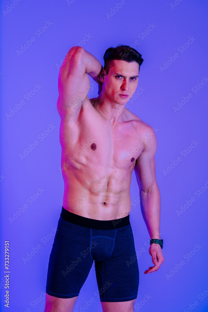 Athletic man with fit muscular body training in studio