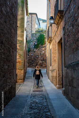 Female tourist strolling through the narrow streets of the medieval town of Caceres, Spain. photo