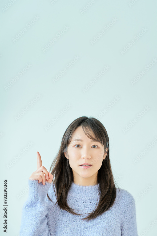 人差し指を上げるポーズをする若い女性