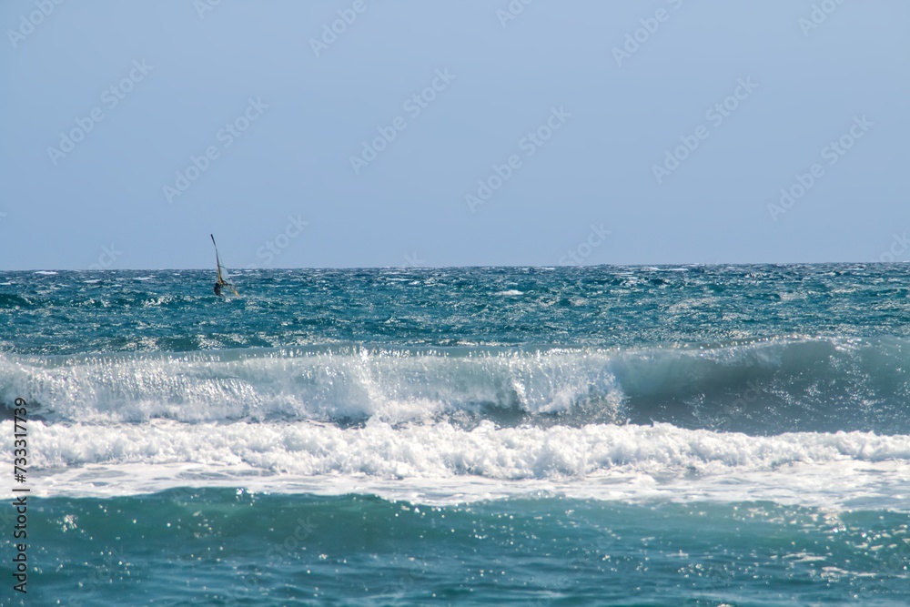 Tabla de windsurf en el mar Mediterráneo en Almería, España. Windsurfista practicando en un soleado día de verano. Playa de Los Genoveses. Tabla de windsurf en el mar Mediterráneo en Almería, España. Windsurfista practicando en un soleado día de verano. Playa de Los Genoveses.