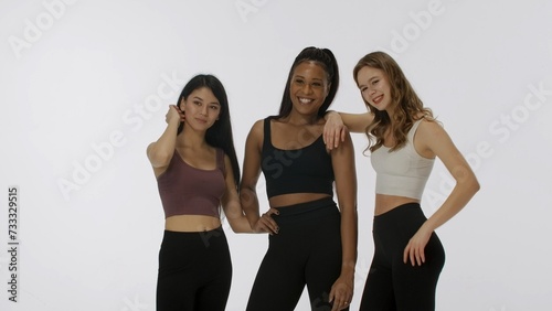 Portrait of young multiethnic models on white studio background close up. Group of three appealing multiracial girls hug and smile at the camera Multiethnic beauty concept.