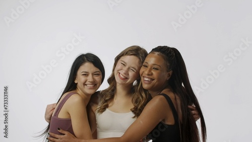 Portrait of young multiethnic models on white studio background close up. Group of three appealing multiracial girls standing posing at the camera Multiethnic beauty concept.