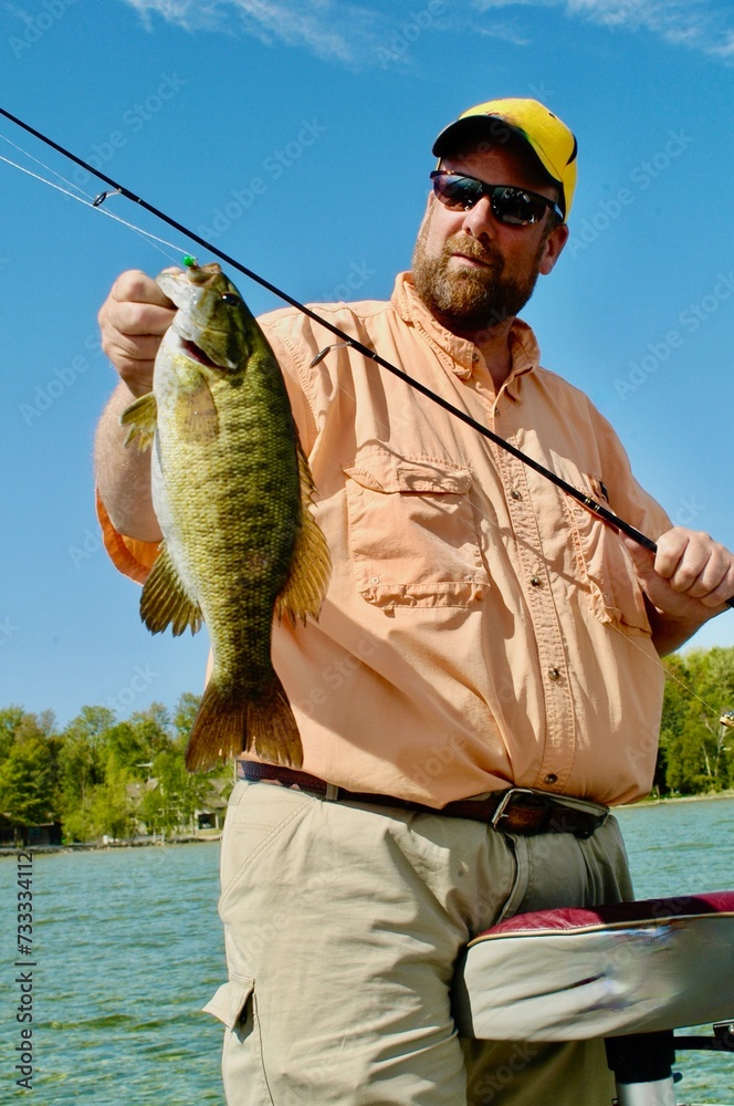Angler with a smallmouth bass  - obrazy, fototapety, plakaty 