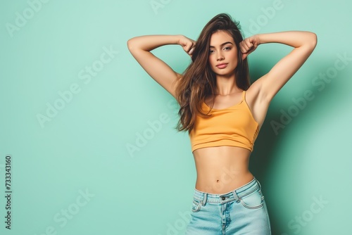 Young woman in tank top raises her arms, her armpits are shaved. Studio photo with copy space.