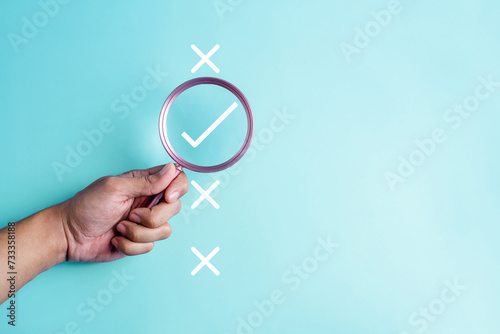 approval, approved, check, checkmark, choice, choose, confirm, correct, cross, decision. hold a magnifying for right or wrong marks on blue background color, the concept of choice without people.