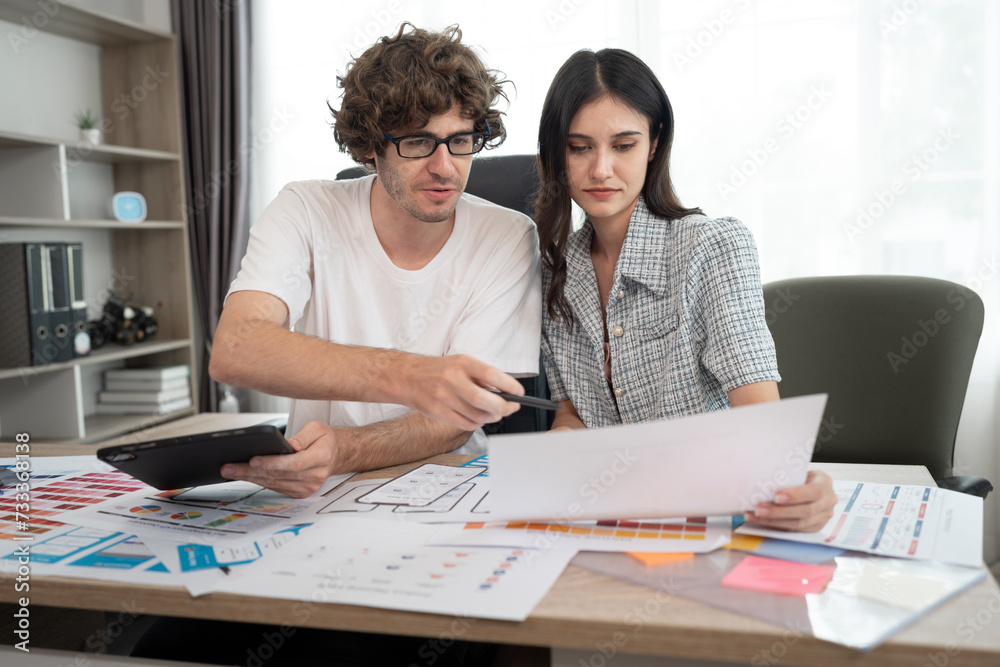 Caucasian businessman and Asia businesswoman working with tablet computer color chart at office	