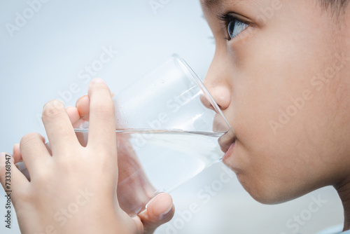 little Asian boy drinks water from a glass. shot of a child drinking a glass of cold water.