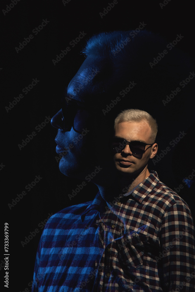 Portrait of a man in sunglasses and a plaid shirt on a black background. Multiple exposure.