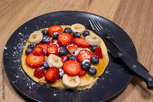 breakfast with pancakes with fruit,breakfast strawberries bananas and blueberries with maple syrup and powdered sugars, gluten free