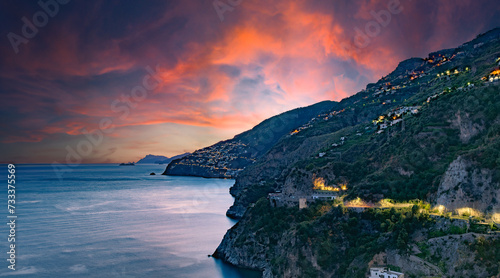 Amalfi Coast, Italy. View over Praiano on the Amalfi Coast at sunset. Street and house lights at dusk. In the distance the island of Capri on the horizon. Amalfi Coast road. Sea landscape. © Alessandro