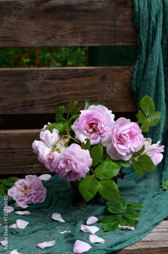 Bouquet of garden pink roses in a vase on a bench in the garden © natalieina17