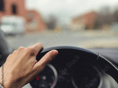 Close-up shot of hand driving a car showing the road